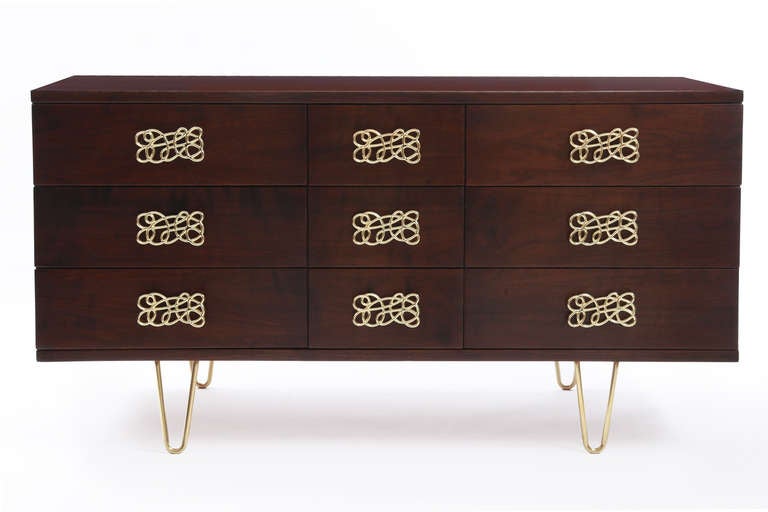 Striking walnut and polished brass chest of drawers circa late 1950′s. This 9 drawer example has sculptural scraffito brass drawer pulls and hand rubbed brass hairpin legs. The walnut case has tapered sides and has been impeccably refinished. Please