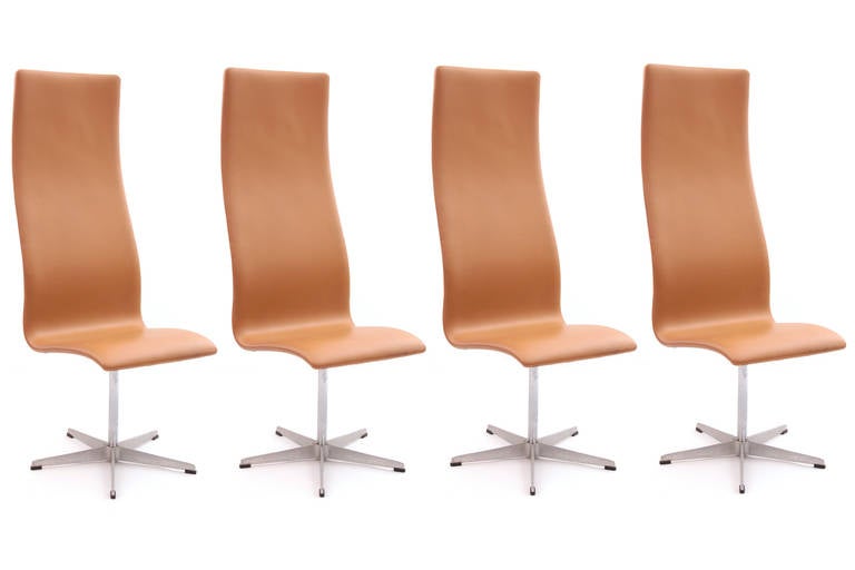 4 Arne Jacobsen for Fritz Hansen high back Oxford chairs circa late 1960's. These examples has star bases that swivel and are upholstered in their original toffee leather. Each of these does have wear to the upholstery and are priced in their