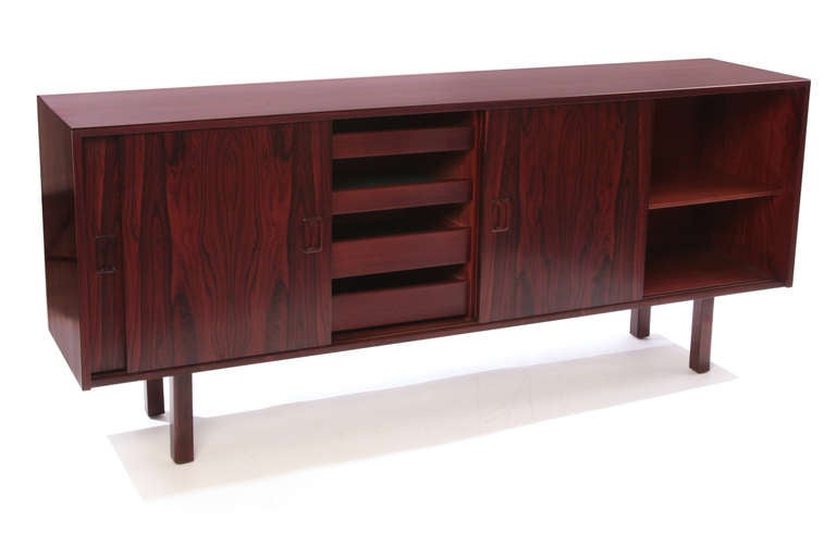 Elegant Brazilian rosewood credenza circa mid 1960's. This  lovely example has four beautifully grained slidiing doors, adjustable rosewood shelves, four center drawers and solid rosewood legs. it has recently been impeccably restored.