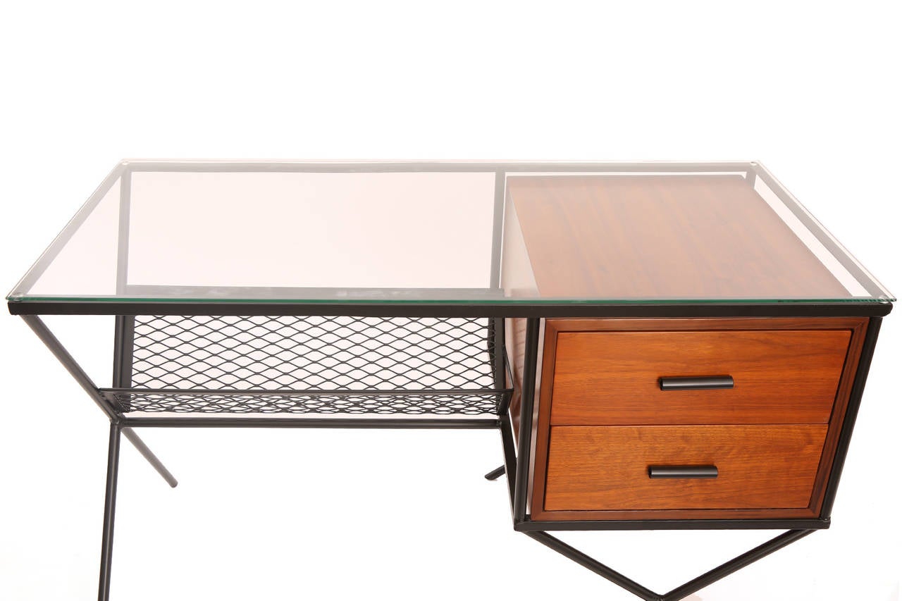 Muriel Coleman for Vista iron walnut and glass desk circa early 1950's. This seldom seen example has a lovely wrought iron frame with x legs and inset metal mesh storage area. The drawers are walnut with iron handles. This example has a new glass