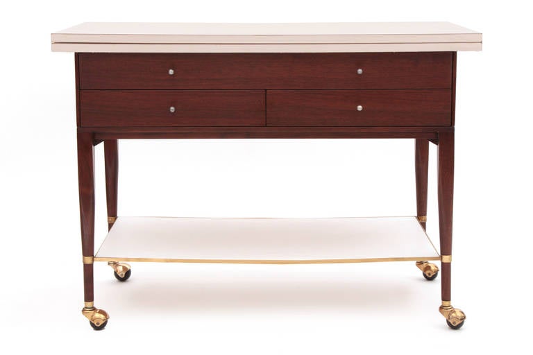 Paul Mccobb for Calvin mahogany and brass bar cart circa late 1950s. This example has solid hand rubbed brass accents, striped African mahogany case and legs and snow white laminate extendable top. The top extends to 80