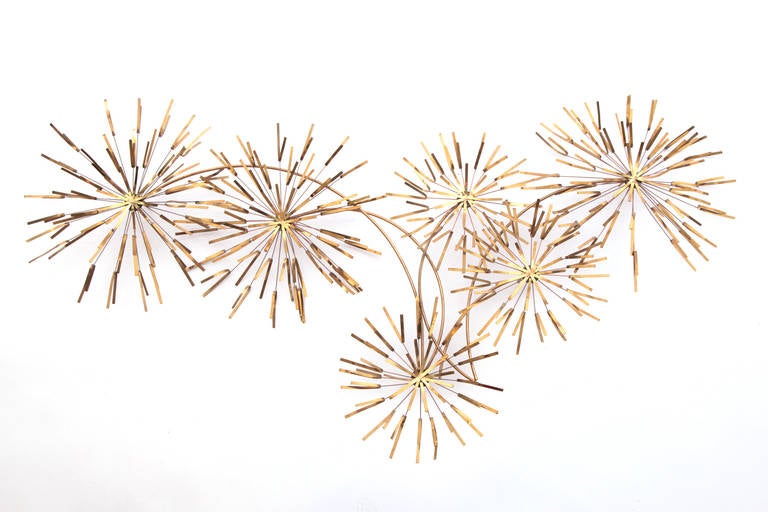 Patinated brass starburst wall sculpture, circa late 1960s. This example has layered starburst or abstract flower elements that actually move to the touch. Can be used indoors or out.