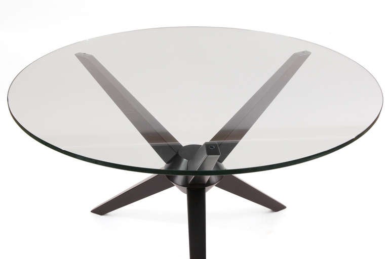 Sculptural ebonized maple dining table, circa late 1950s. This example has three subtly tapered legs that intersect into an architectural centerpiece. It has been newly finished in a Steinway black lacquer. The current glass top is 47