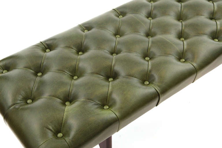 Diamond tufted kelly leather bench. This chic example has a beveled solid mahogany h base that has been newly finished. This bench has also been upholstered in a stunning and supple  leather with diamond tufting and buttons. Please see our other
