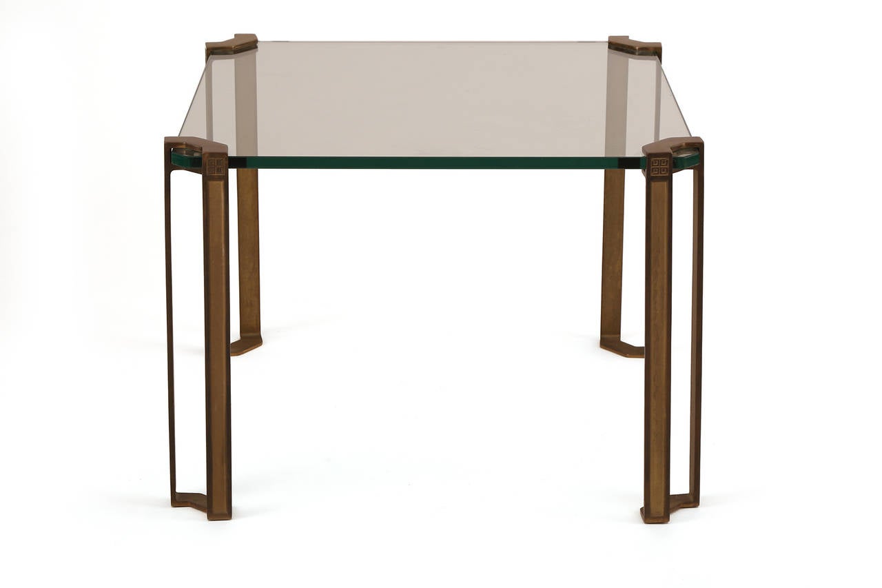 Stunning bronze and glass side or cocktail table by Peter Ghyczy, circa early 1970s. This example handsomely wraps around the glass top with solid bronze legs with architectural detailing.