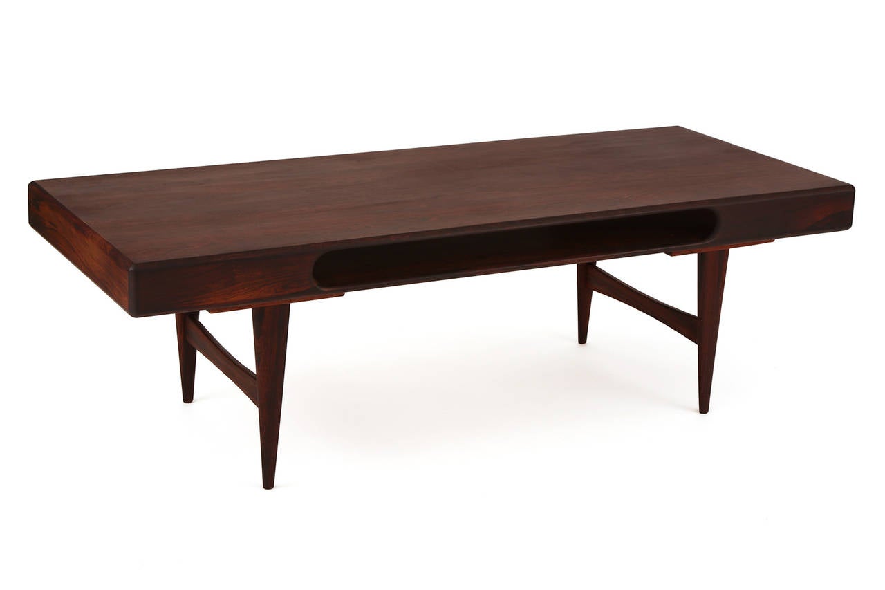 Rosewood cocktail table from Denmark, circa early 1960s. This example has a cutout center for a wonderful sculptural form and added storage. Has beautiful graining to the top and the legs and stretchers subtly taper. Newly finished.