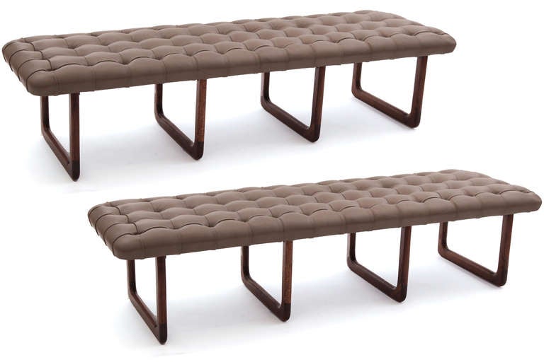 Pair of leather and solid walnut benches. These elegant examples have subtly curved corners stunning button tufting and have been newly upholstered in a supple stone gray leather. Each bench has four solid walnut u shaped bases. These can be sold