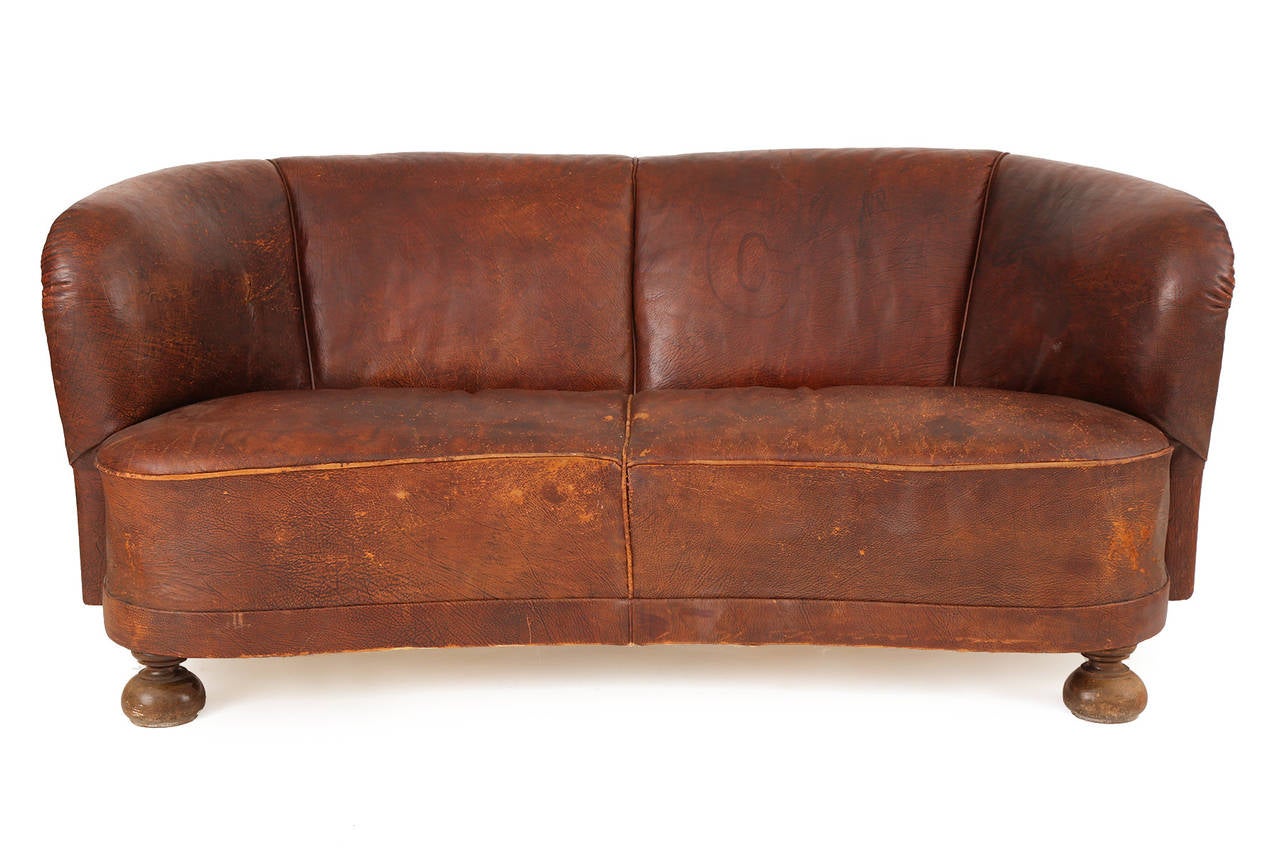 All original free-form sofa from Denmark, circa 1930. This lovely example is upholstered in a beautifully broken in riveted cognac leather with solid beech legs. From an important Danish estate.