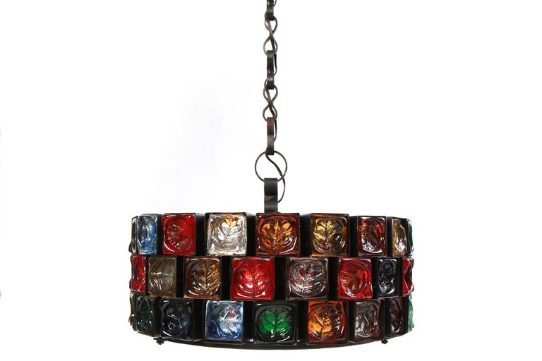 Wrought Iron and hand blown glass chandelier from Mexico circa early 1960's. This three tiered example has an embossed leaf in each piece of glass. The glass ranges in color from reds to blues to greens to amber. This takes 4 bulbs and when