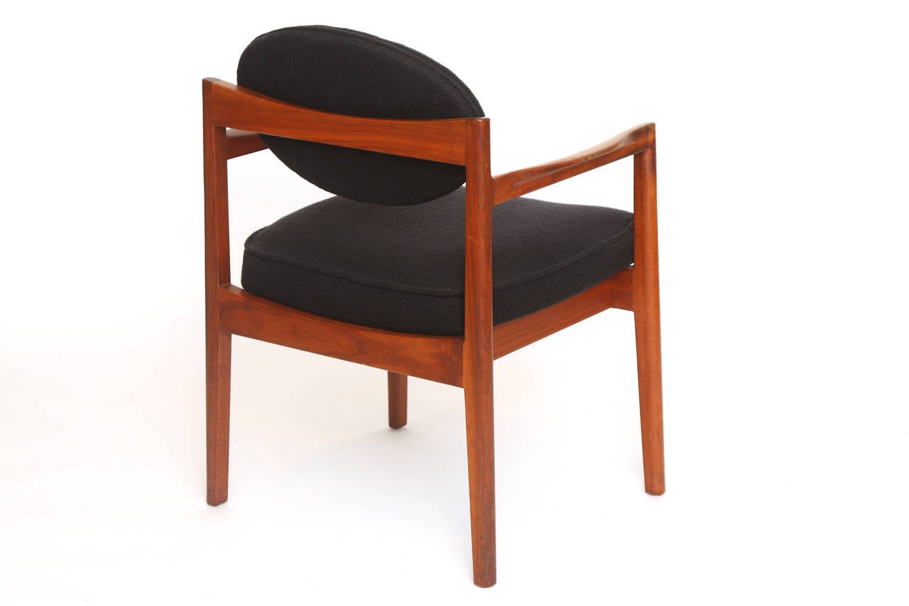 Set of eight sculpted walnut and upholstered armchairs by Jens Risom, circa mid-1960s. These examples have solid walnut frames with flared arms and floating backs. They are upholstered in their original black heathered bouclé. Price listed is for