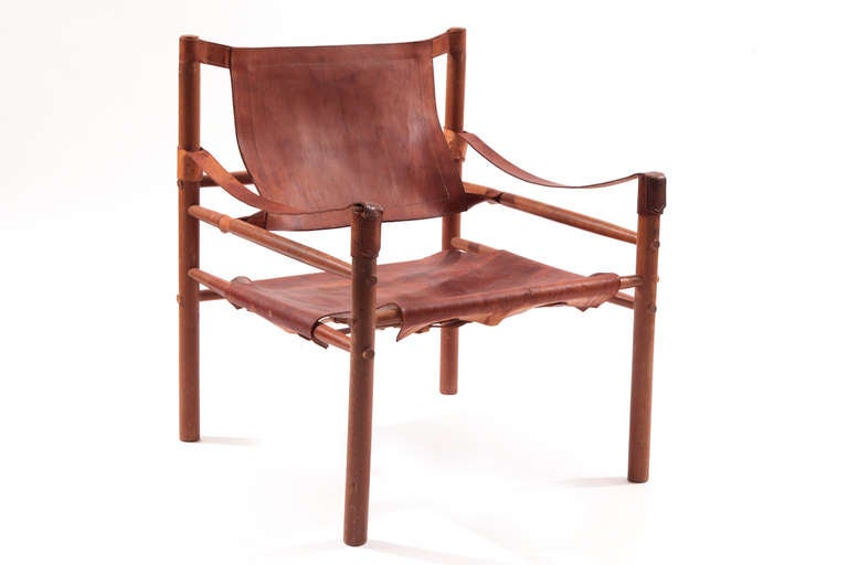 Pair of Arne Norell Safari chairs, circa late 1950s. These all original examples have heavily patinated caramel leather slings buckle detailing and solid beechwood frames.