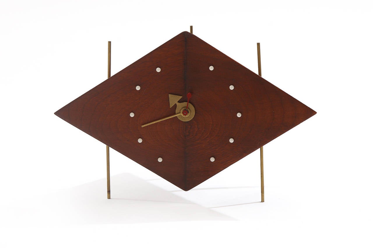 Original George Nelson for Howard Miller kite clock from 1957. This extremely rare example has a suspended solid walnut case with three patinated brass legs. Original clock motor hands and enameled metal hour indicators.