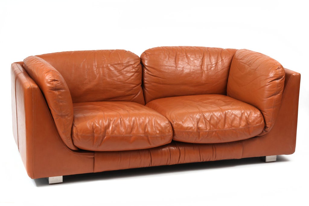 Beautifully patinated Desede leather love seat and ottoman circa late 1960's. This example has French seaming on all cushions and on the sides and back of the sofa. The color is a rich butterscotch and the feet are inverted chrome squares. Price is