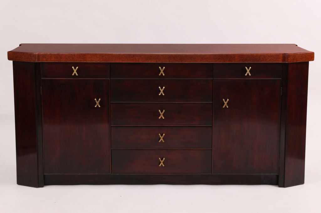 Paul Frankl for Johnson Furniture Company sideboard, circa early 1950s. This example is done in striped African mahogany and has seven drawers and two doors with interior storage. The X-pulls are solid brass and the solid cork top has been newly