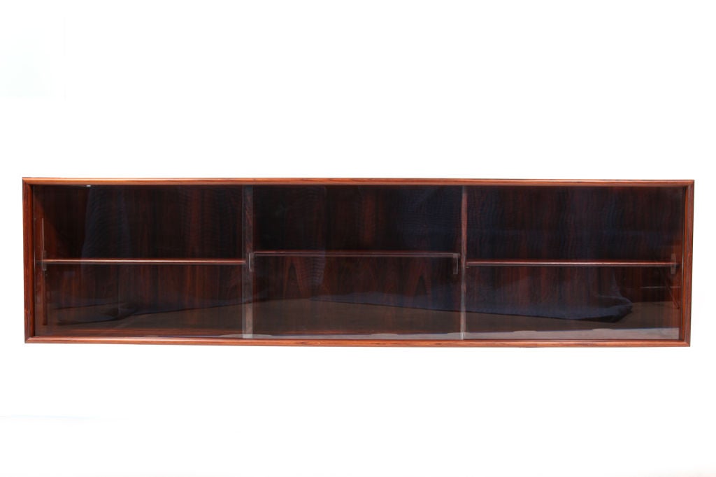Rosewood and glass floating wall credenza from Denmark circa late 1960s. This example has wonderfully grained Brazilian rosewood with three sliding glass doors and adjustable interior shelves.