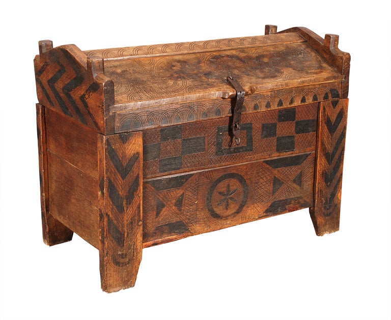 An oak and fruitwood coffer with peaked, hinged lid and stained geometric decoration. Also with incised decoration throughout.
