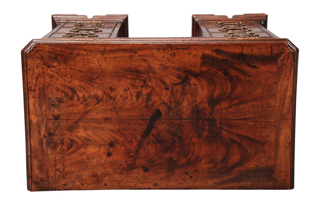 A Chippendale period mahogany kneehole chest with rococo handles and raised on ogee bracket feet. The cock-beading around the drawers is carved to look like braided rope. Also with blind fret decoration on the frieze drawer as well as the canted