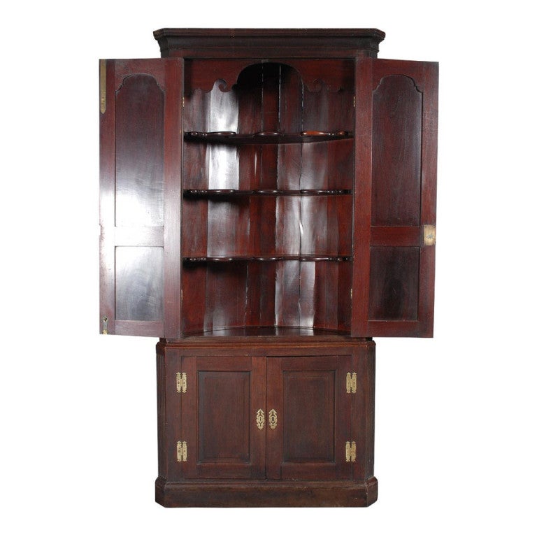 A fine mahogany corner cabinet with arched panel doors.  The fielded panel doors hung on brass H-hinges.  The interior with fixed shaped shelves.