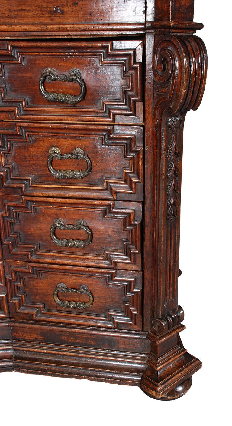 The four heavily molded drawers rest below a single frieze drawer.  Also similarly molded on the sides.  The projecting corners are carved with scrolling corbels.  Raised on the original flattened bun feet. Richly patinated with the beautiful grain