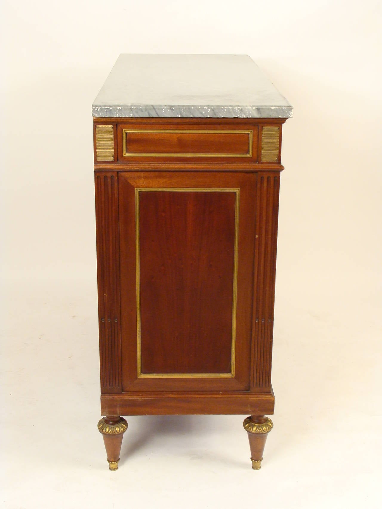 Maison Jansen style Louis XVI mahogany buffet with gilt bronze trim and a marble top, mid-20th century. This cabinet exhibits exceptional workmanship and materials throughout.