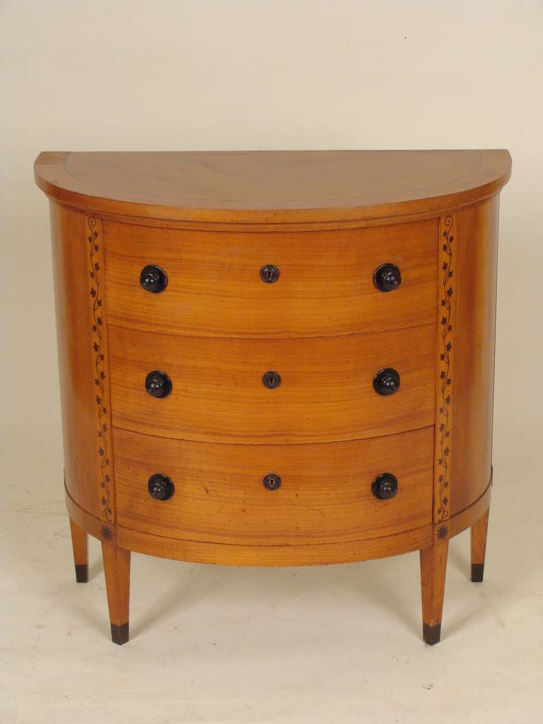 Biedermeier revival demi lune birch commode with ebonized highlights, mid 20th century. There is a brass plate in the top drawer that is stamped Brauer & Wirth Stuttgart.