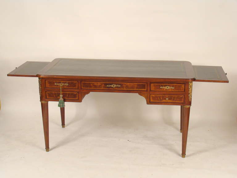 Directoire style mahogany leather top desk with gilt bronze mounts, circa 1920. This desk features include plum pudding mahogany drawer fronts, side panels and back, gilt bronze mounts and a dark green tooled leather top.