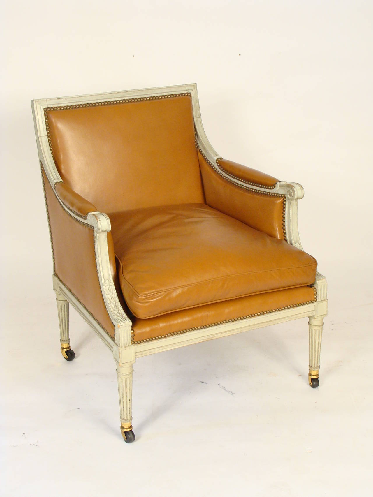 Pair of painted Louis XVI style leather upholstered bergeres, circa 1960.