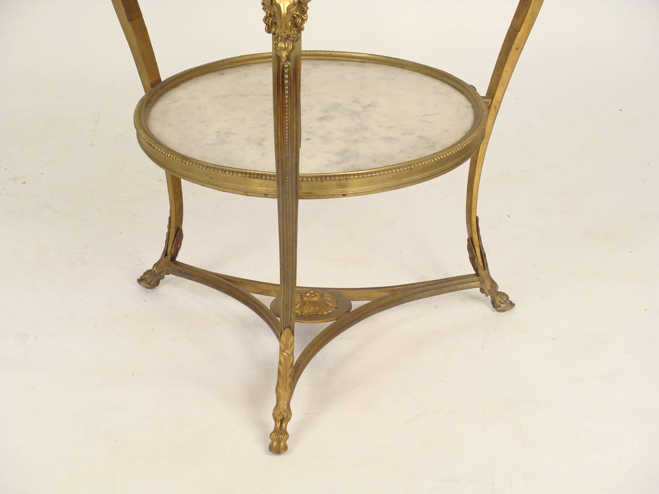 Directoire style gilt bronze and marble Gueridon, made circa 1970. This is a very stylish neoclassical table with a Carrara marble top, well defined ram head mounts on legs, resting on hoof feet.