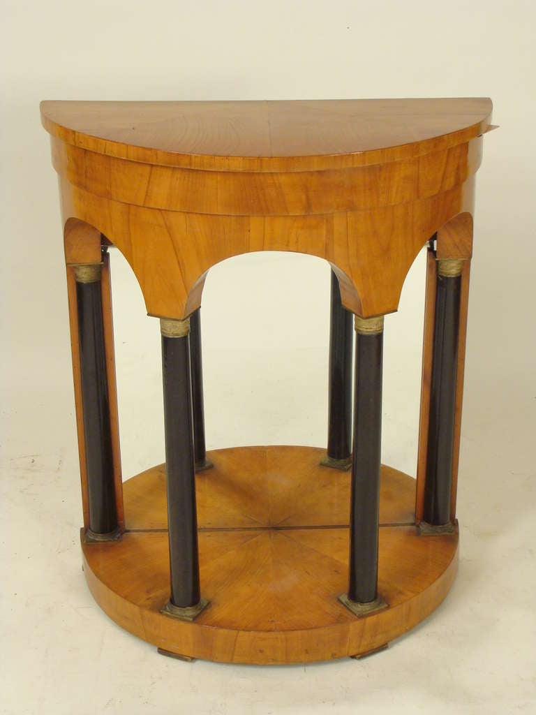 Biedermeier demi lune birch console table with ebonized columns, brass mounts and a later mirrored back, circa 1830. This console table has very nice color and would go well with a neo classical or contemporary interior.