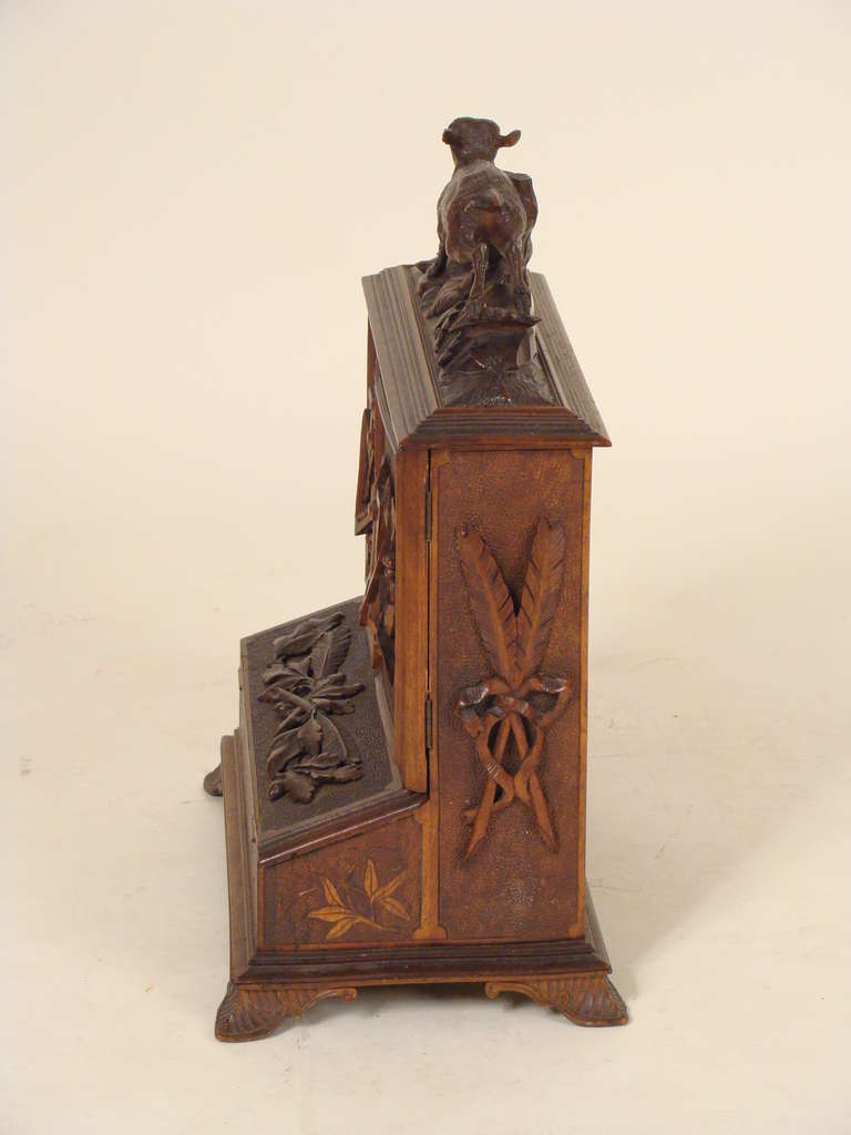 Carved walnut black forest letter box, circa 1900. Featuring a carved doe on top  of two foliate carved doors that open to reveal letter holders a foliate carved slant top which opens to reveal an ink well.
