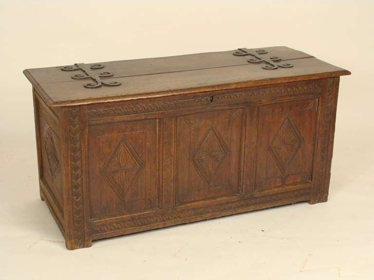 Early 19 century Tudor style oak trunk with unusual decorative iron hinges on top. Three front and two side panels with diamond designs.