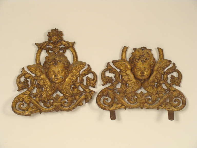 Pair of  gilt iron architectural fragments with cupid heads, 19th century. Both fragments have loses. These architectural fragments would go well in a rustic romantic room setting. The dimensions are different on both pieces due to loses. The