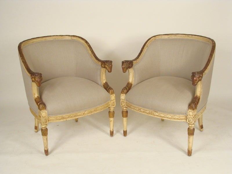 Pair of neo classical painted and partial gilt bergeres with ram head arms, circa 1920-1940