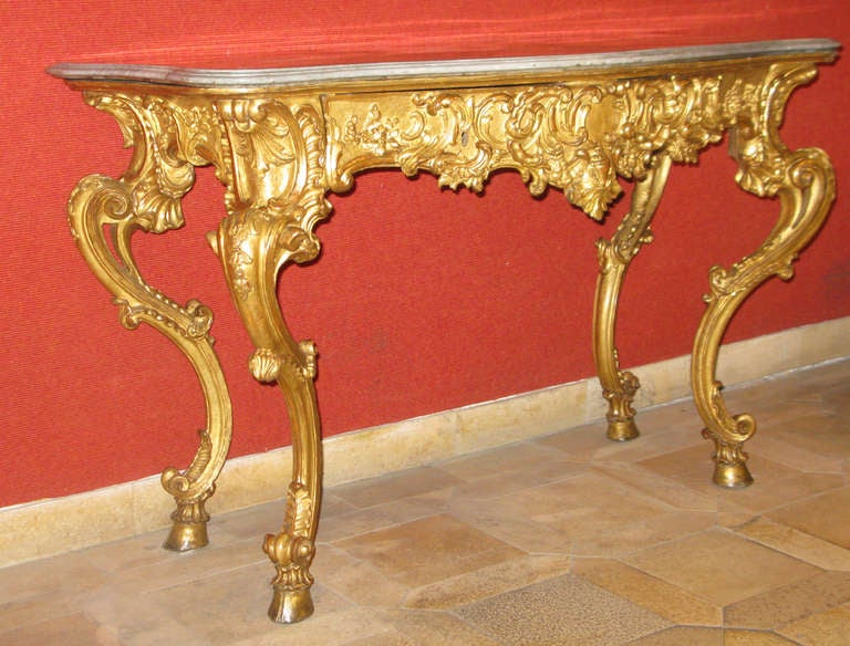 A mid-eighteenth century gilded and carved console of vigorous and exuberant design and movement.  Self-supporting on four exaggeratedly curved legs which have an open work inner scroll.  The legs are covered with carved scrolls, foliate and beading