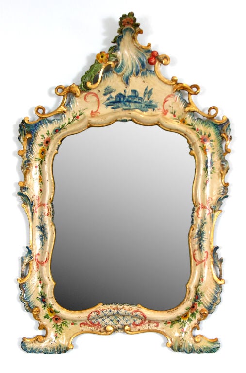 A fine mid-eighteenth century ivory based lacquered ‘toilette’ or dressing table mirror of shapely form, with tall crown.  The rocaille carving is lacquered blue.  The volute in gilt wood and foliate and floral decorations.  The base with a net, the