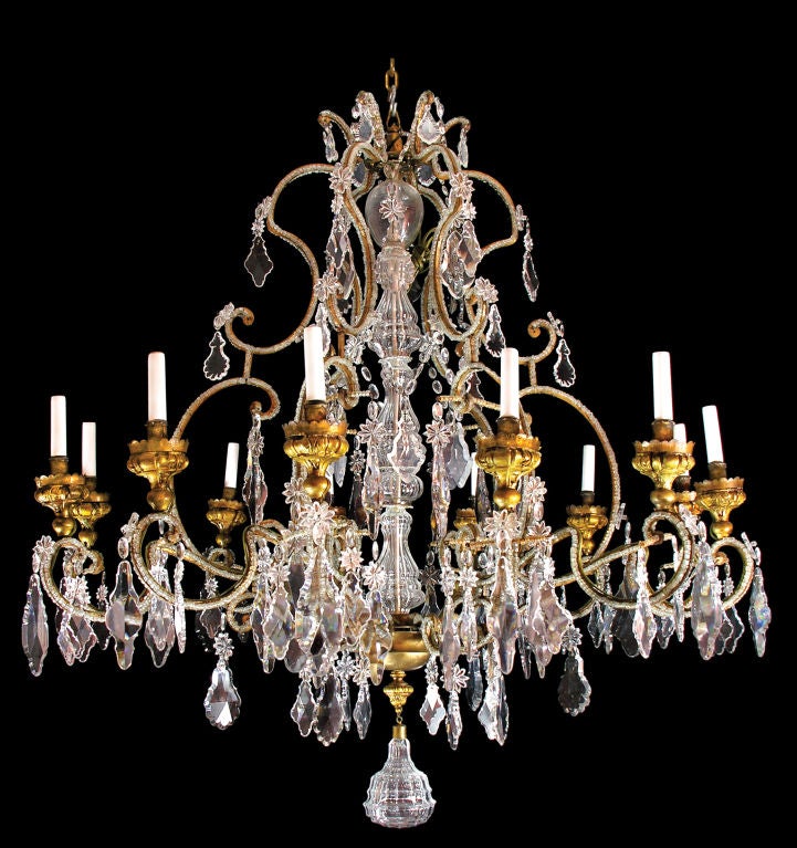 An unusually brilliant twelve light worked metal and crystal chandelier with metal arms closely covered with crystal beading. With gilt metal bôbeches and a central shaft covered with four crystal glass forms. Drops of many various tear-drop and
