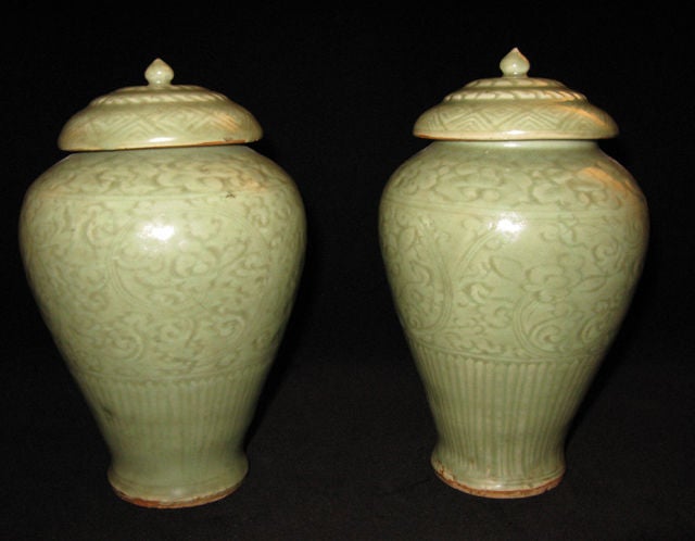 The vases carved with floral scrolls above a band of vertical lines, the covers with central knops and carved with various geometric designs. Celadon glaze refers to a family of transparent, crackle glazes, produced in a wide variety of colors,
