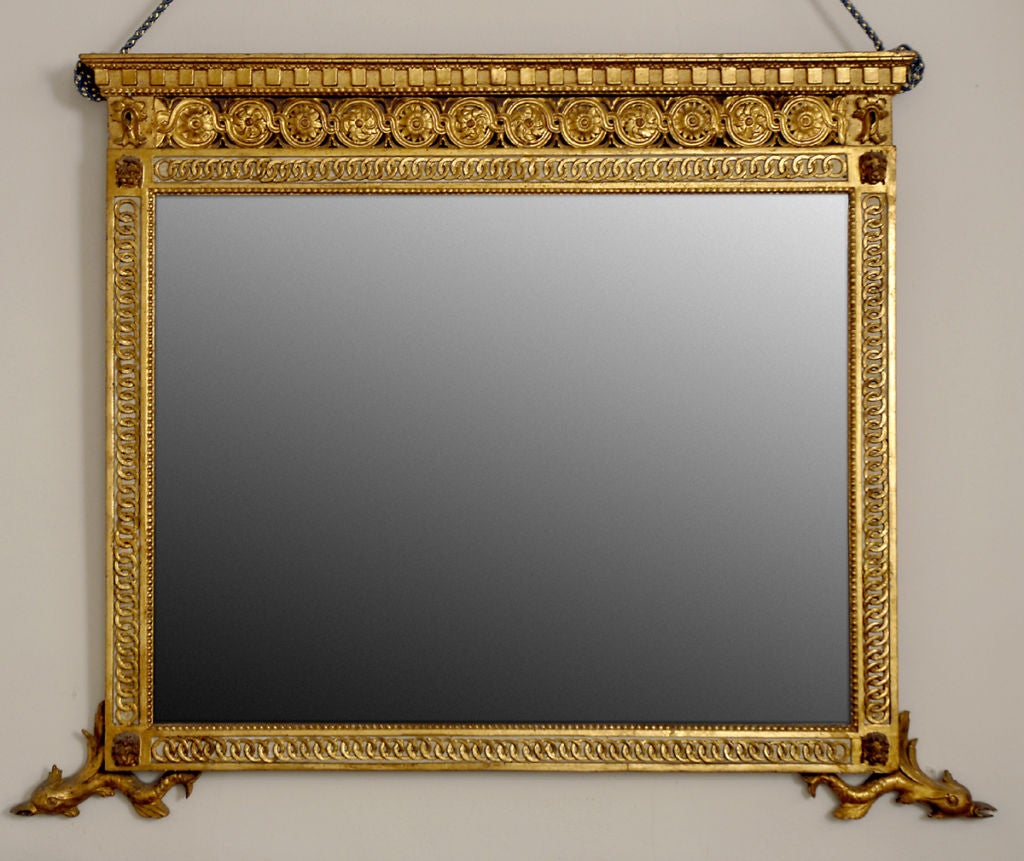 A carved, with original painted accents, parcel gilt looking glass, also with original mirror glass. With dentil cornice over a frieze with running rosettes, with patera on the corners, terminating with a palmette motif. The uprights and horizontal