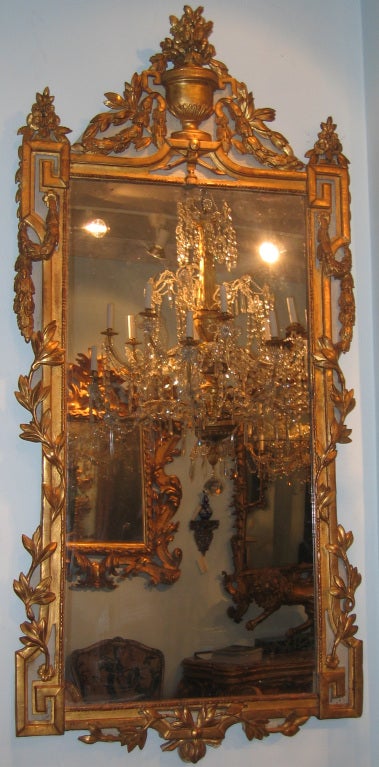 A Louis XVI painted and gilded wood mirror with Greek key design and vines trailing in and out of molding, and an urn with flower garlands at the summit.