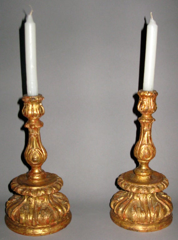 A very finely carved pair of gilded wood candlesticks.