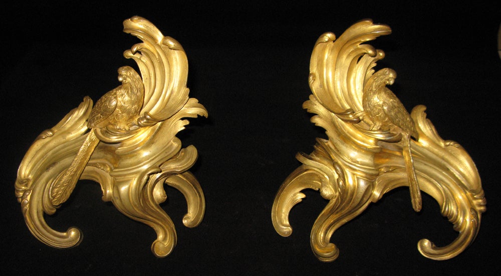 A Louis XV pair of very finely gilded and chased bronze chenets with scrolled foliate cast base; depicting birds perched on top.