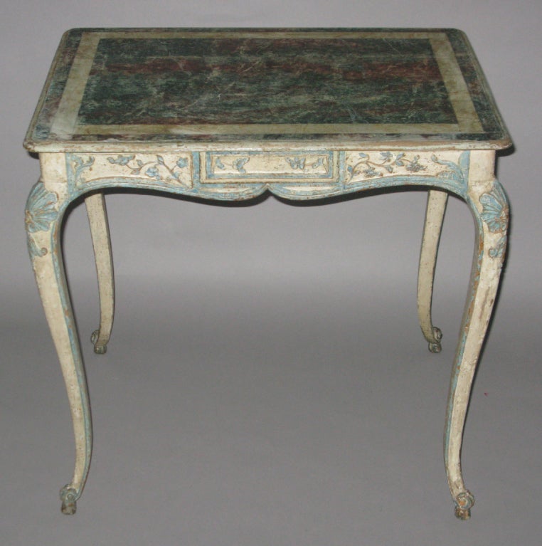 A single drawer painted blue and white table with faux marble painted top, the shapely frieze decorated all around with blue painted floral carving; the cabriolet legs with blue trim, floral carving on top and ending in scrolled feet.