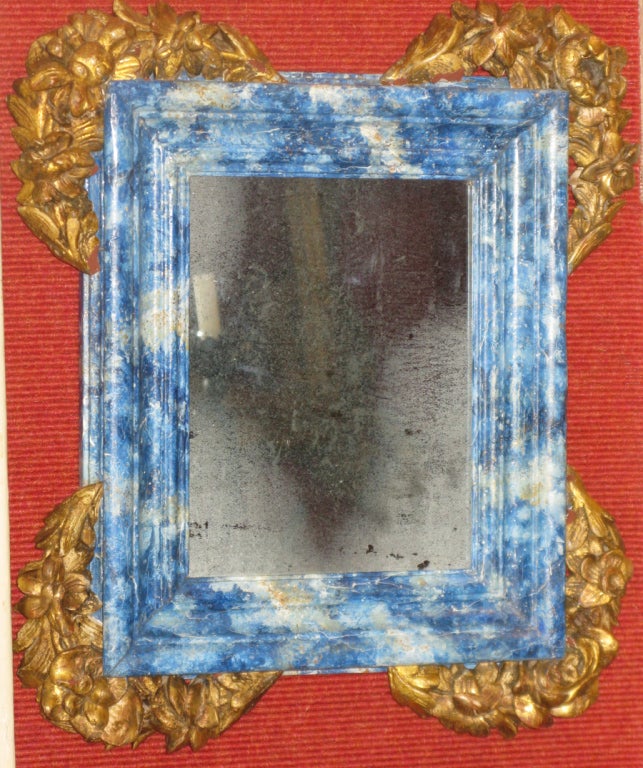 An Italian 19th century blue painted marbleized mirror frame with hand carved and gilded floral corners; with antique mercury mirror.