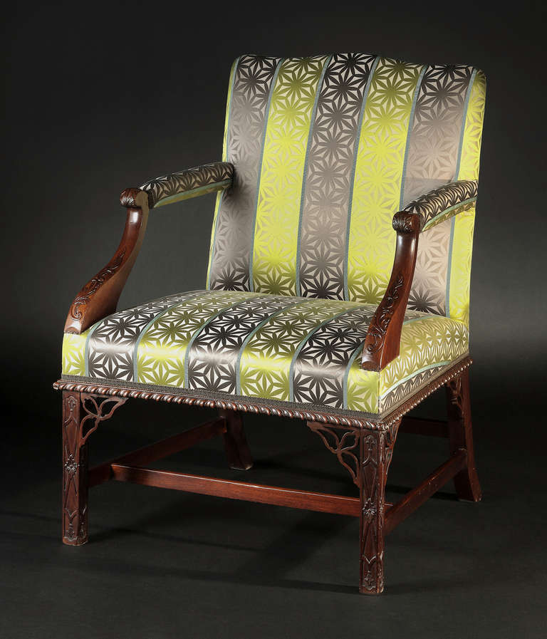 The upholstered serpentine back issuing padded armrests with foliate carved uprights and over-upholstered seat with gadrooned rail; raised on square legs with conforming decoration, headed by pierced brackets and joined by an H-form stretcher.
