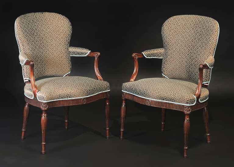 Each with upholstered cartouche-shaped backrest issuing channeled down-swept supports; the over-upholstered seat above serpentine stop-fluted seat rail with turned and fluted legs headed by floral roundels.