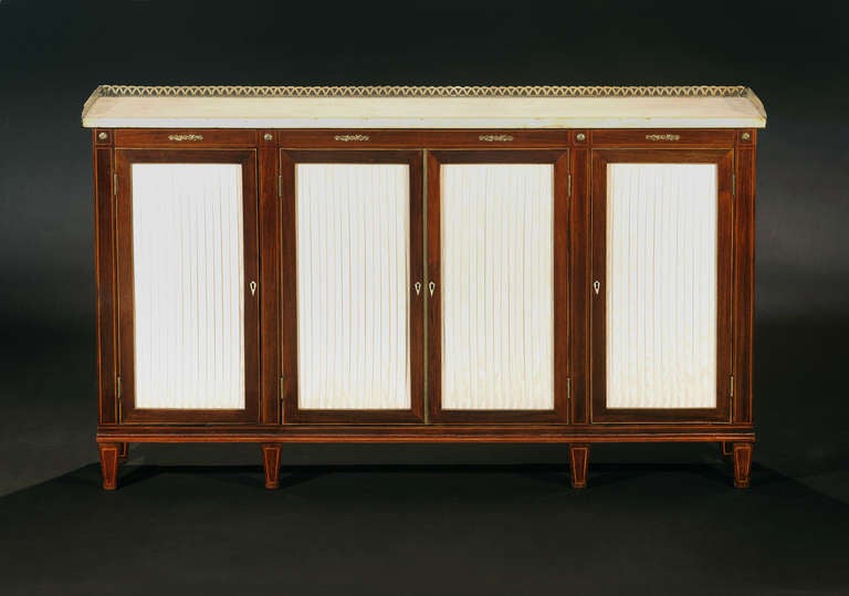 The rectangular marble-top with pierced brass three-quarter gallery above four silk-lined doors, raised on tapering feet.