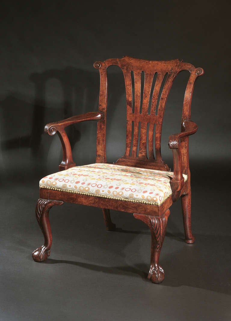 The pierced backplates flanked by conforming stiles, set below a scroll form crestrail; the shaped arm rests with scroll terminals, above an over upholstered seat and solid seat rail; raised on acanthus leaf carved cabriole legs terminating in ball