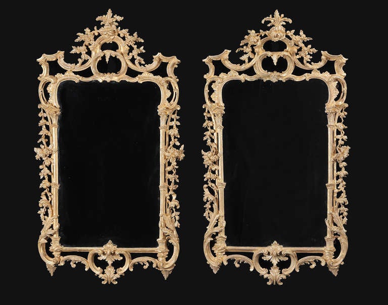 The later plates set within a shaped surround incorporating classical rockwork, enclosed by symmetrical acanthus leaf sprays; the sides hung with floral carving, below a pierced crest surmounted by conforming foliate swags.