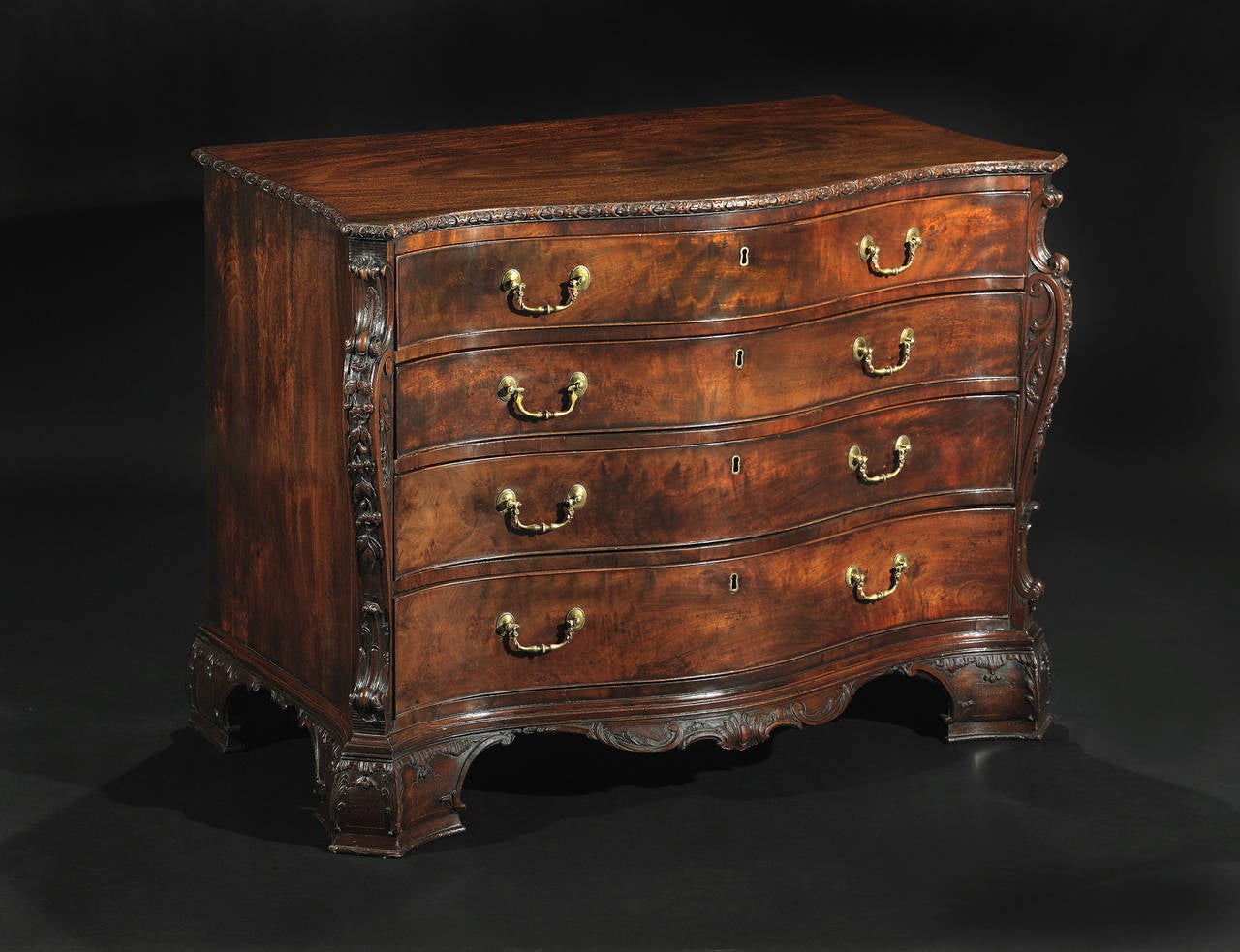 In the manner of William Vile, with foliate carved corbels set at the canted corners, flanking a partially fitted dressing drawer above three additional long drawers, set above a finely carved apron and bracket feet of conforming acanthus leaf