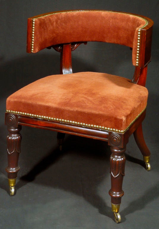 The horseshoe-shaped padded back over molded stiles inset with foliate-carved spandrels; raised on ring-turned and lotus leaf-carved tapering legs headed by applied rosettes; on casters.
